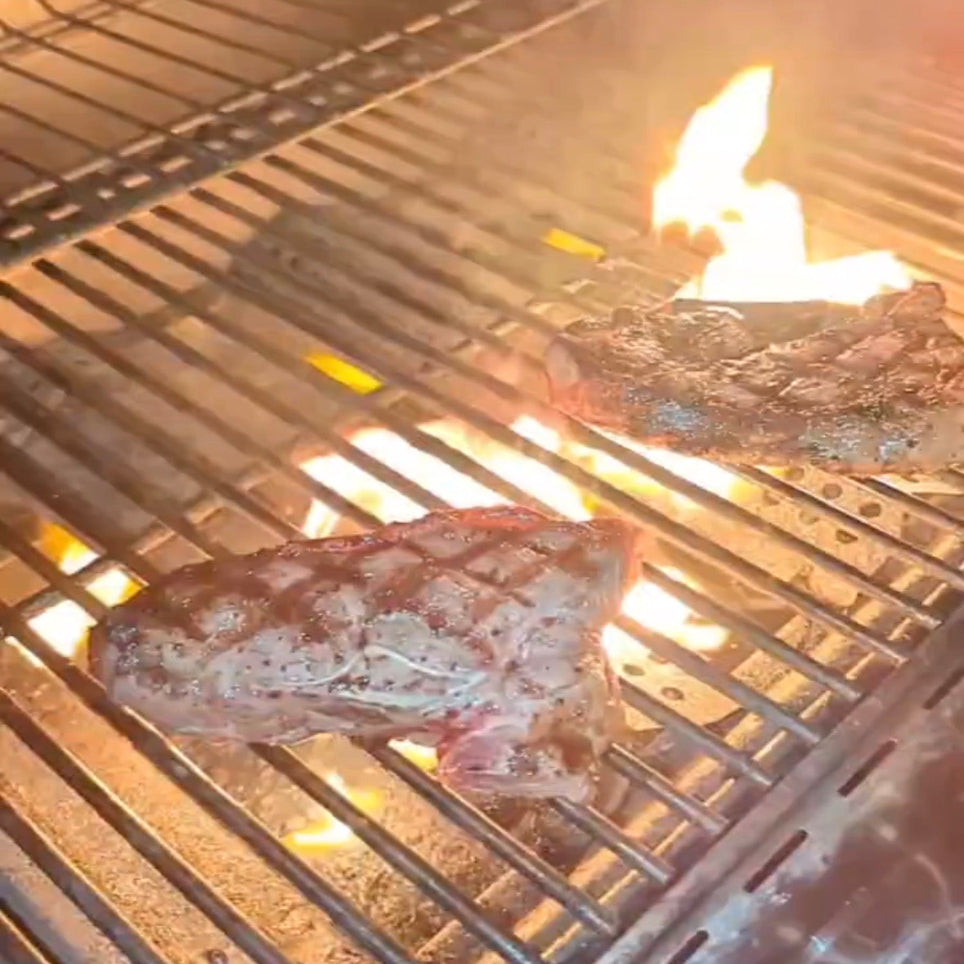Meat cooking on a grill with flames